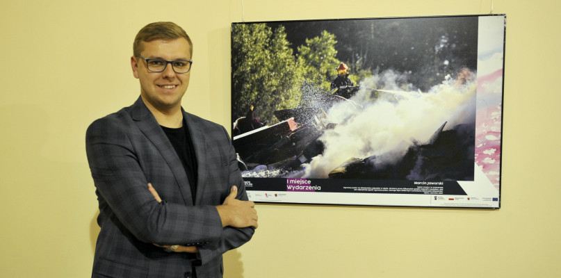 Marcin Jaworski obok zdjęcia swojego autorstwa, które zdobyło główną nagrodę w kategorii Wydarzenia w konkursie Kujawsko-Pomorskie Press Foto. /fot. Maciej Kamiński